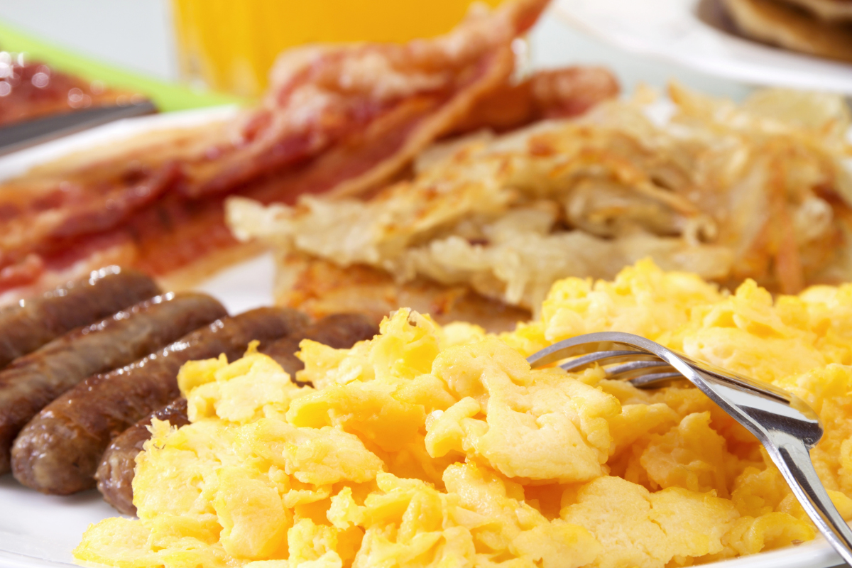 A plate of eggs, sausage, bacon and toast.