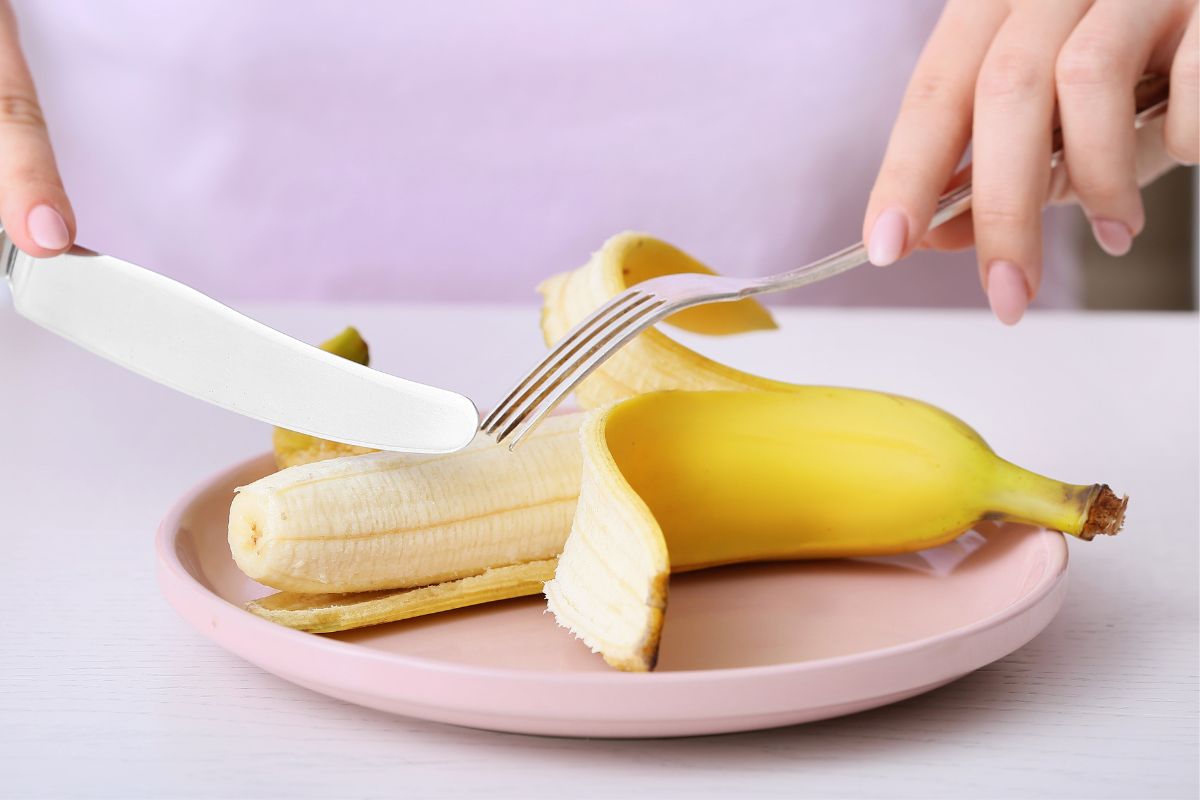 a banana being eaten with a fork and knife