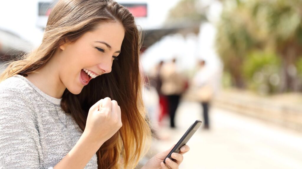 excited woman fist pumping with phone