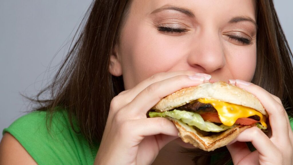 happy woman eating large burger