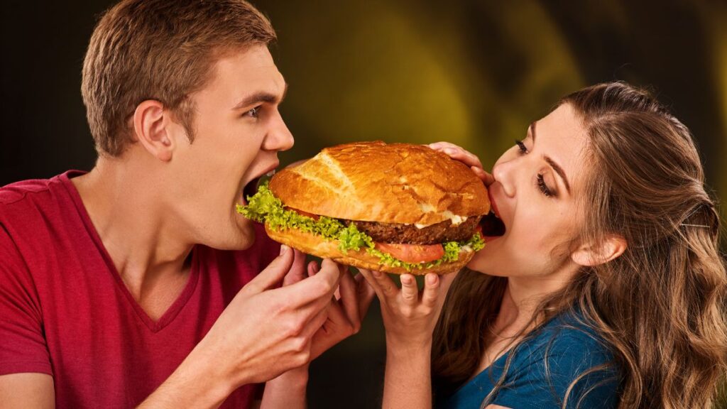 man and woman eating large fast food burger