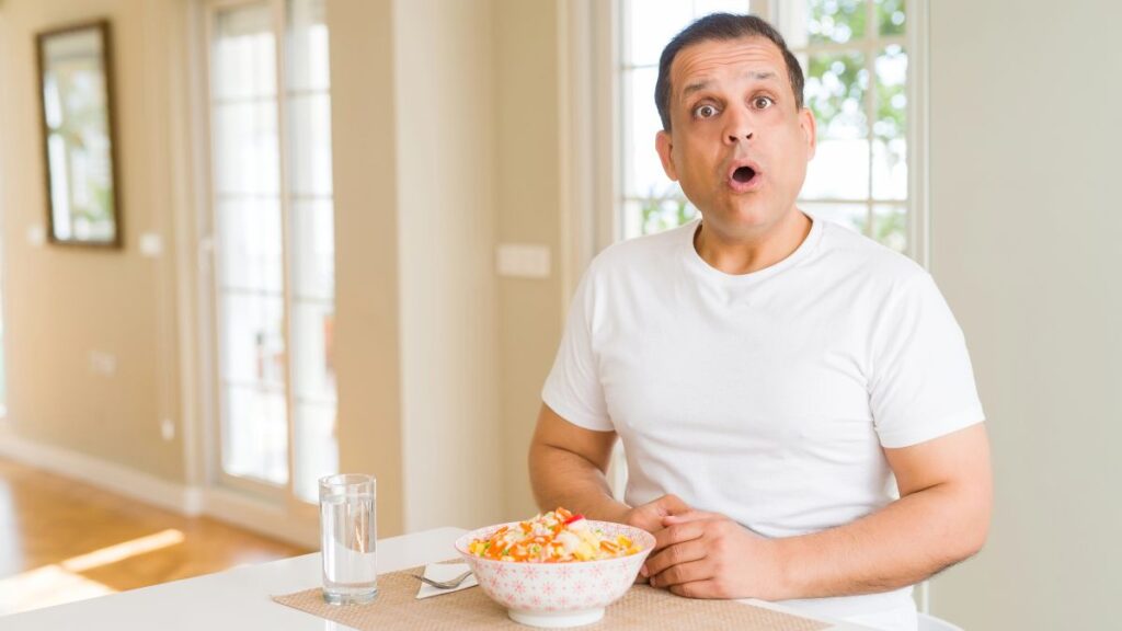 man in kitchen looking surprised with food