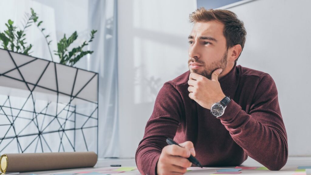 man sitting at desk thinking and writing