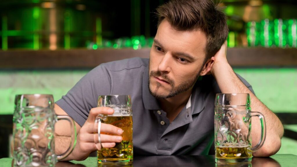 man with drink looking sad at bar