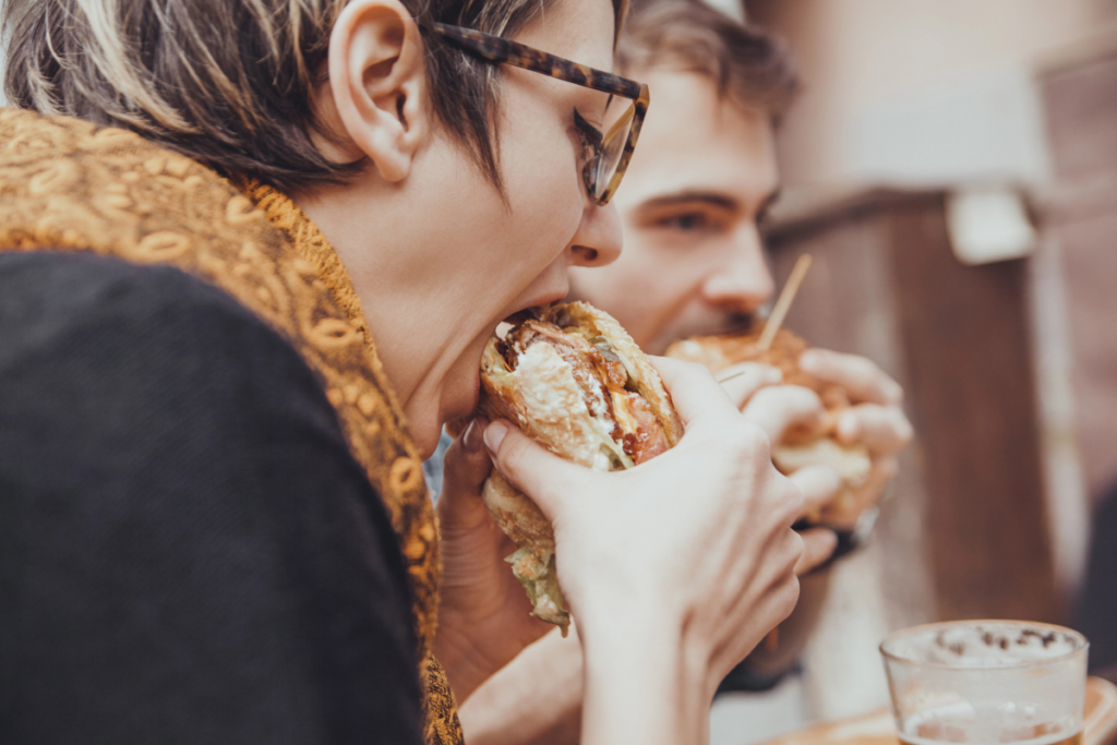 woman and man eating a burger image credit Depositphotos Dangubic.