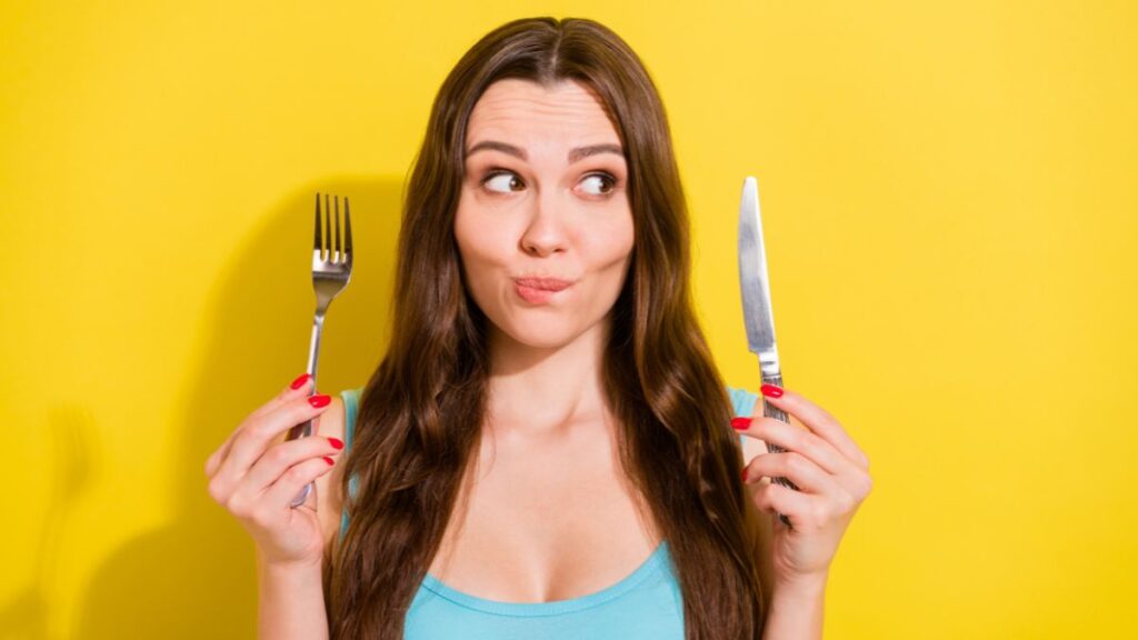 woman looking suspicious holding fork and knife