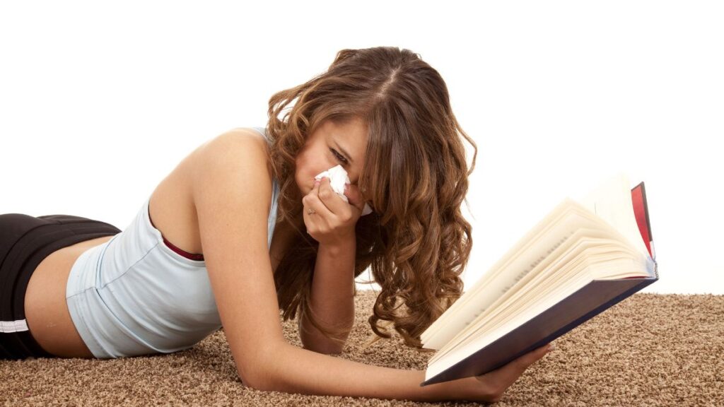 woman reading book blowing nose