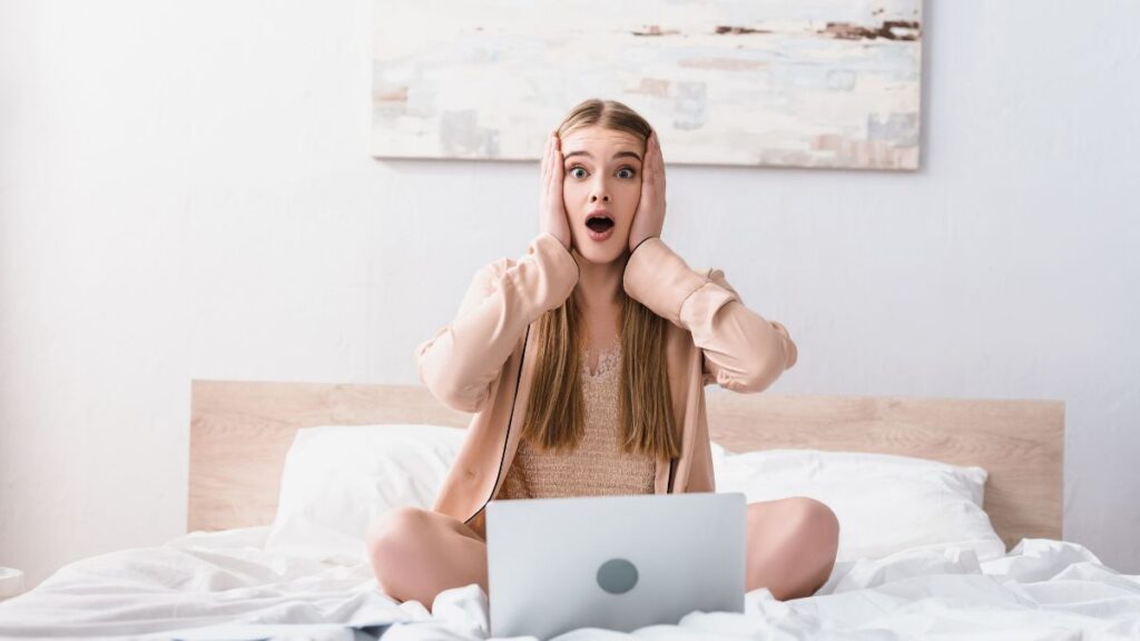 woman surprised at computer with hands on face