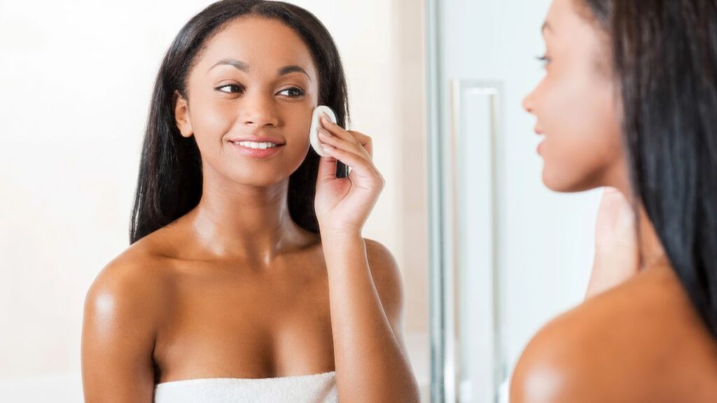 woman with face pad looking in mirror