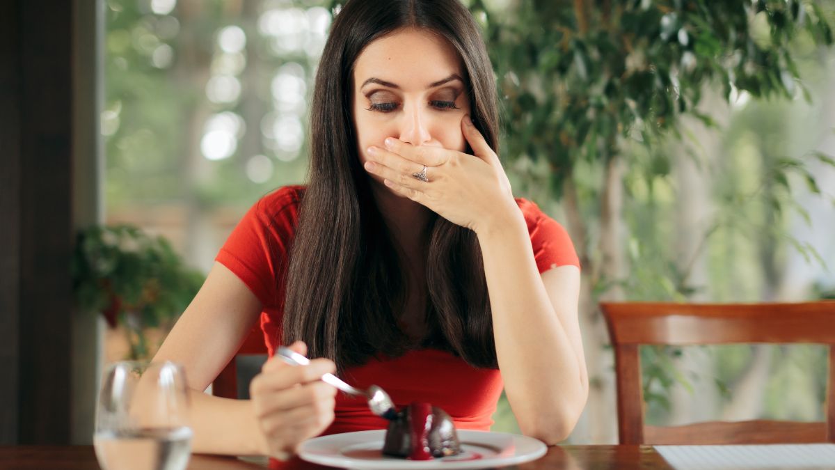 woman with food looking disgusted hand over mouth