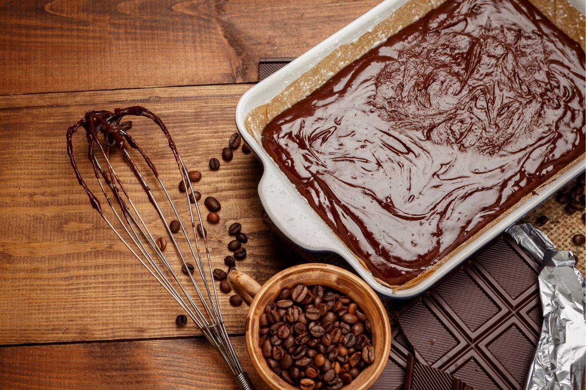 Baking with chocolate, whisk, tray, chocolate bars and coffee beans on the table.