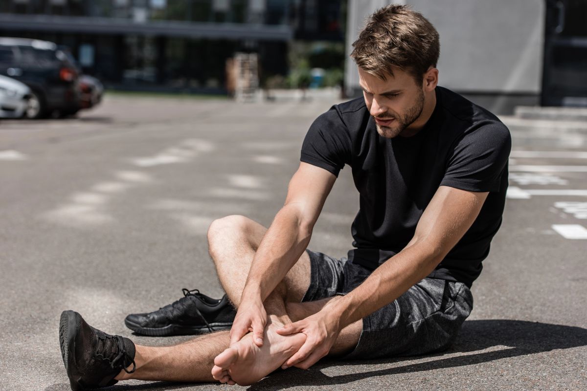 Man holding his feet in the street