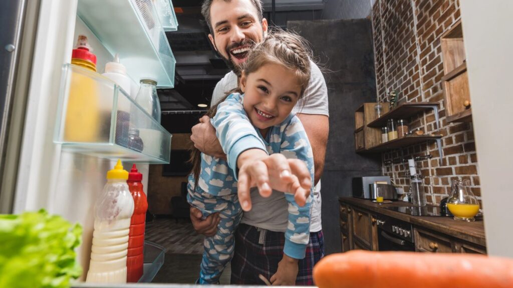 dad and daughter reaching for food in fridge