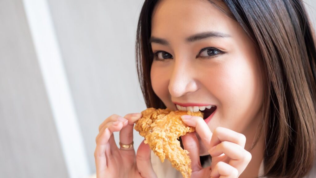 happy woman biting a friend chicken wing