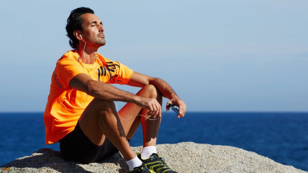 healthy man sitting on cliff in the sun