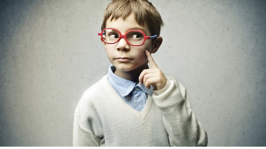 little boy looking away with finger on face