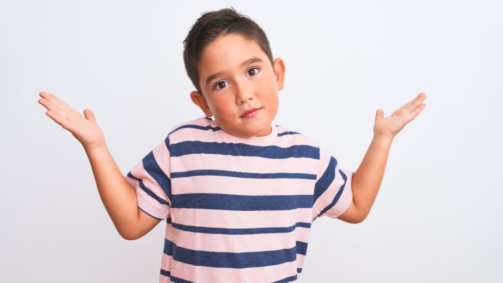 little boy looking confused with hands up