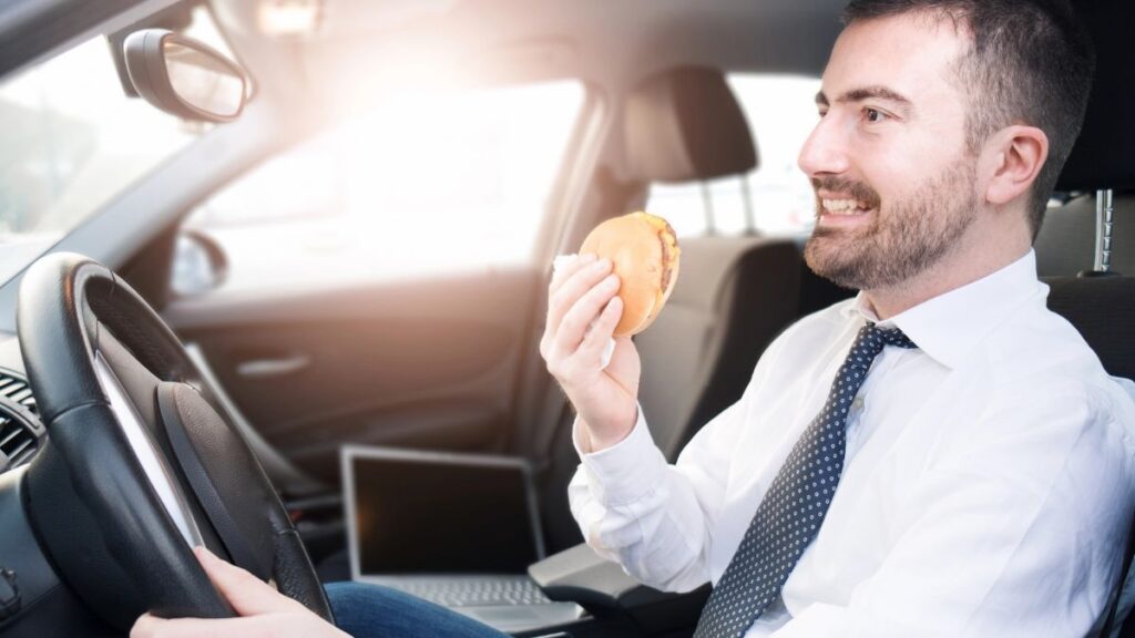 man driving with burger