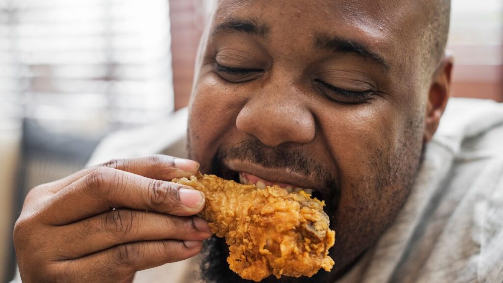 man eating fried chicken drumstick