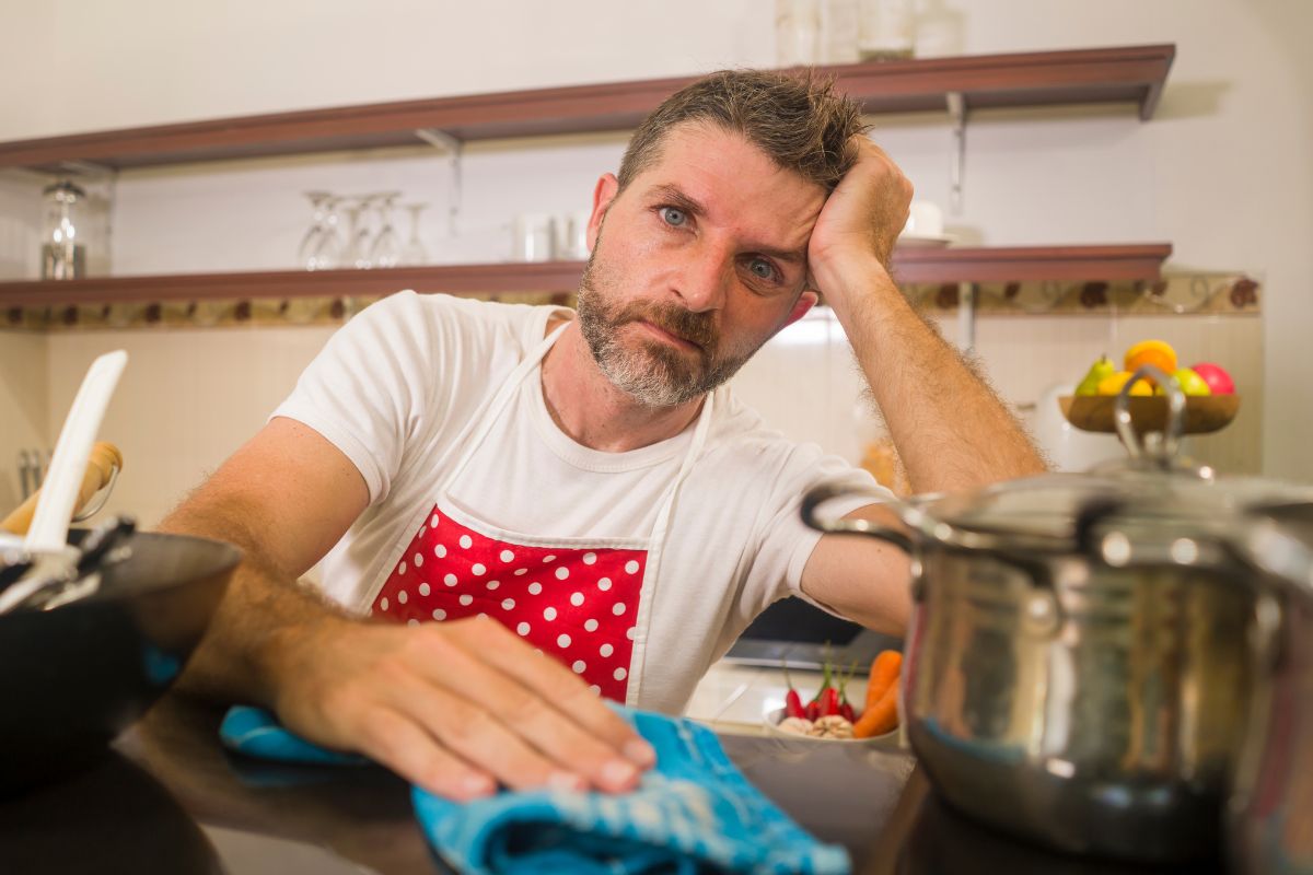 man frustrated in the kitchen wearing a red polkadot apron