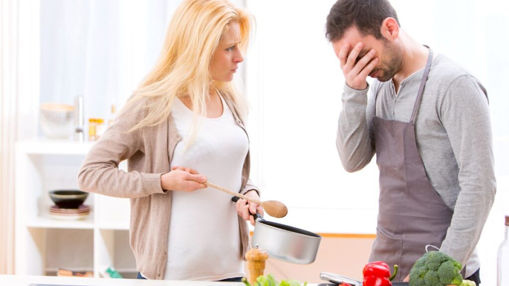 man frustrated with woman holding pot in kitchen