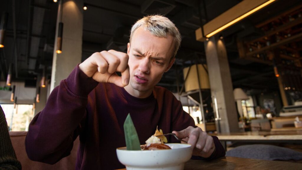 man looking disgusted with hair in food