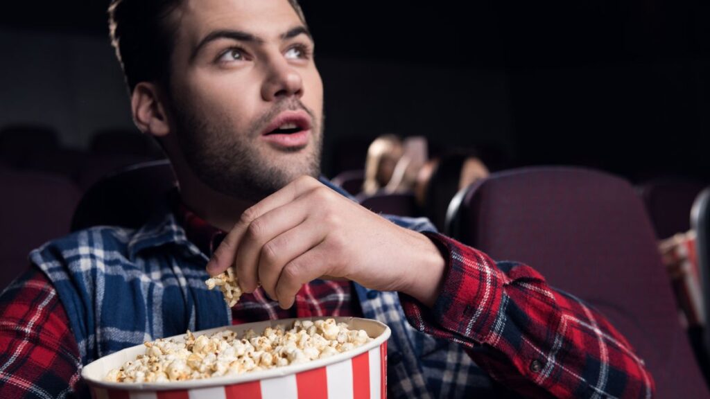 man watching a movie with popcorn