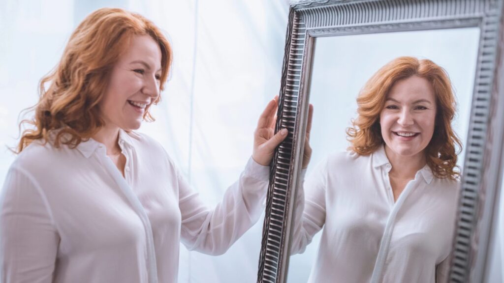 older woman looking in the mirror smiling