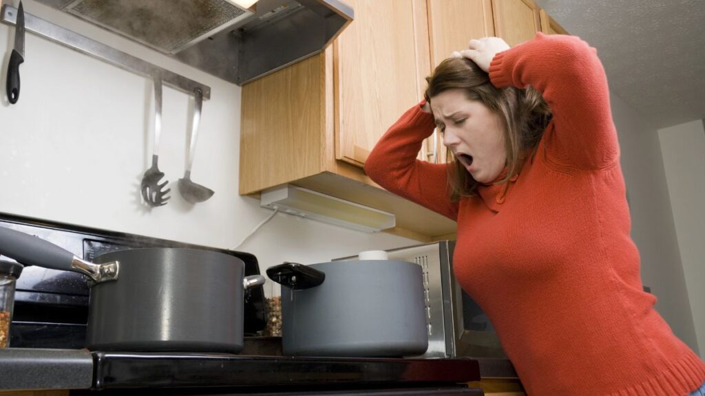 upset woman looking at pot on stove