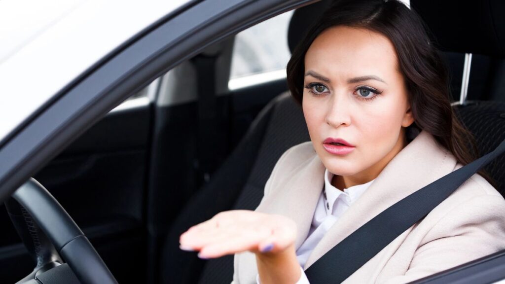 upset woman with hand out in car