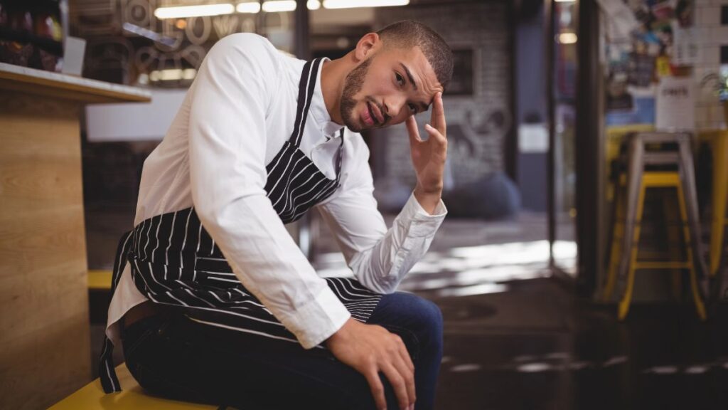 waiter sitting and looking stressed with hand on head