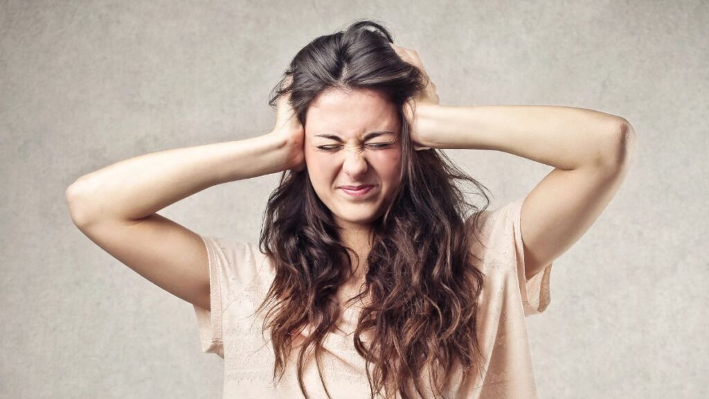 woman covering ears with eyes closed