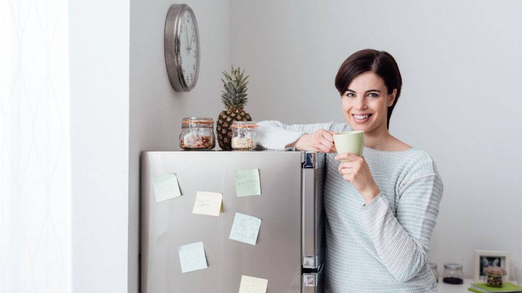 woman leaning on fridge with coffee