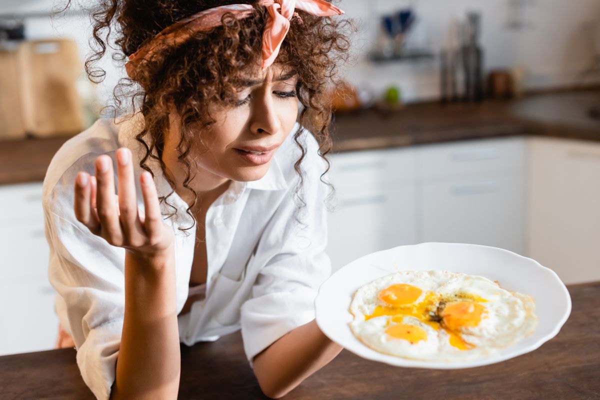 woman looking at a plate of eggs unhappy