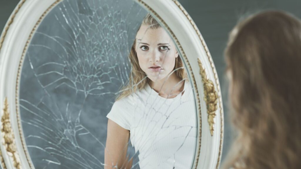 woman looking in broken mirror