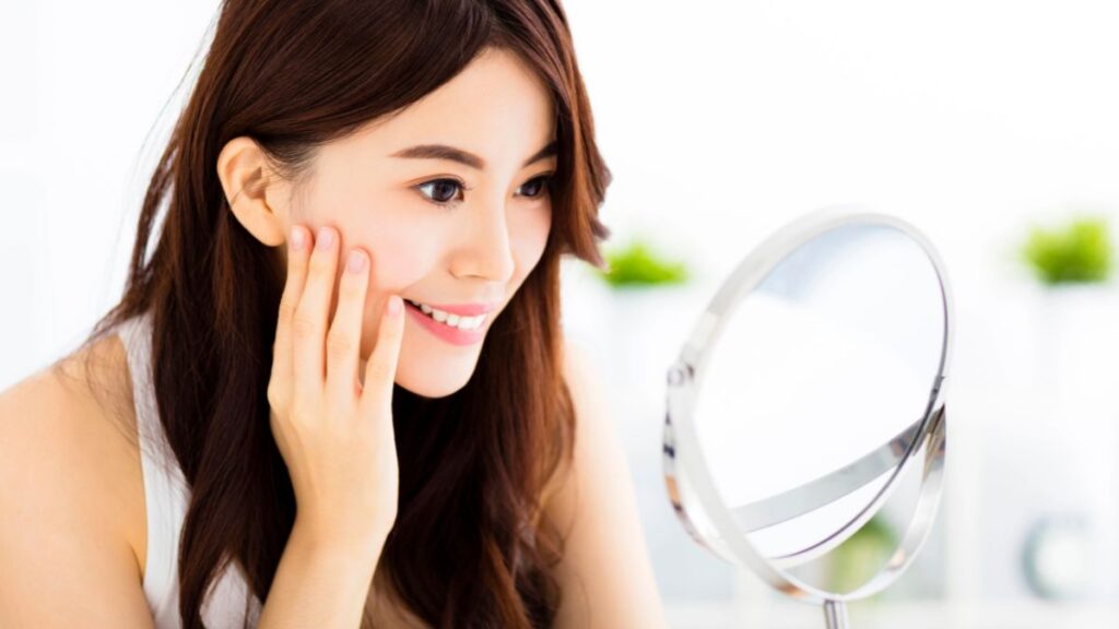 woman looking in mirror at healthy skin