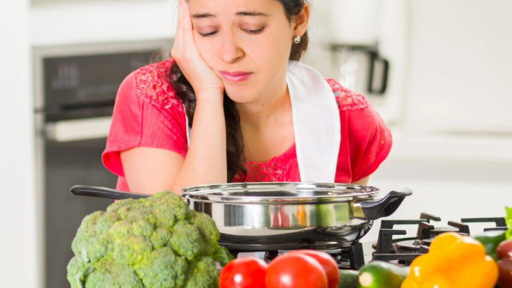 woman looking upset in the kitchen cooking