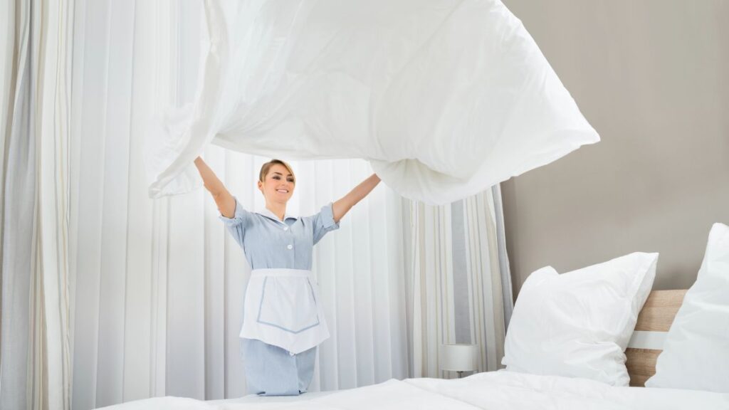 woman making bed at hotel