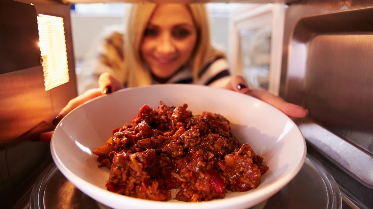 woman removing food from microwave