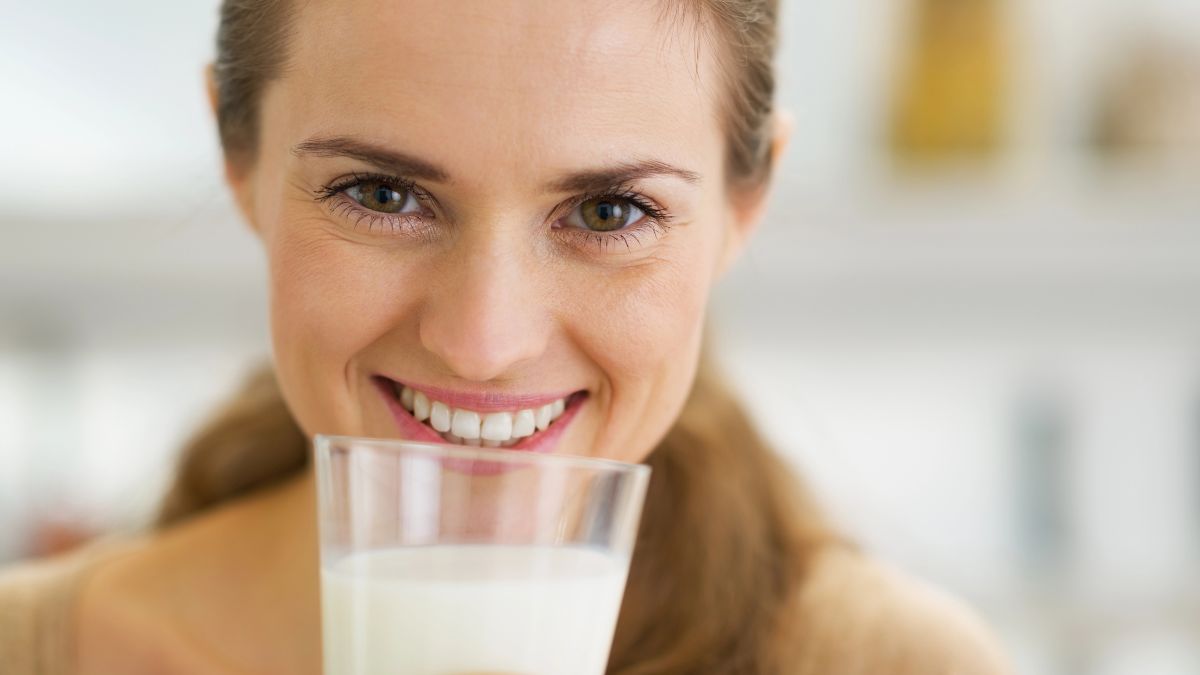 woman smiling with glass of milk