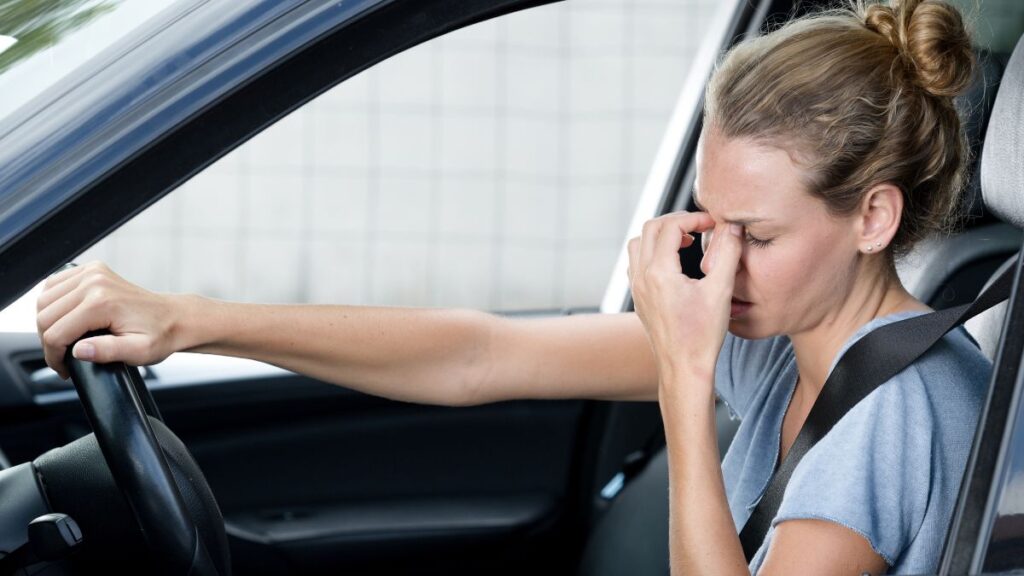 woman upset in drivers seat holding her nose