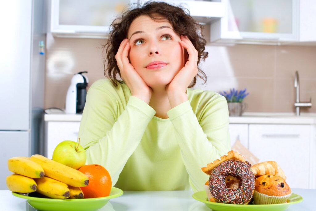 woman with a plate of fruit and donuts thinking