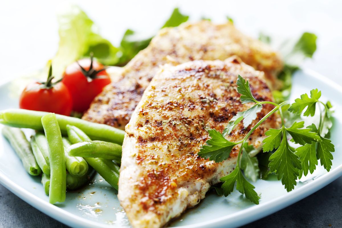 A Plate with chicken breast and veggies around it