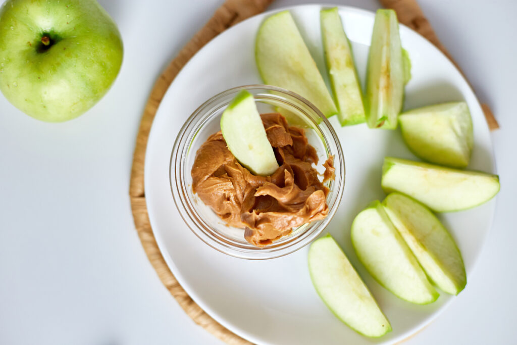 Green slices apples with peanut butter on white background, healthy snack, nutrition food, diet