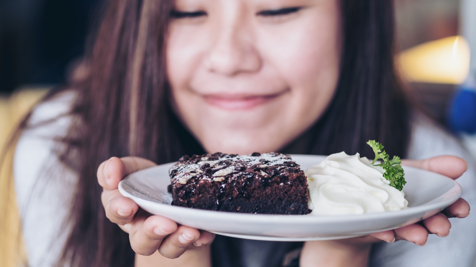 Asian woman holding brownie and whip cream