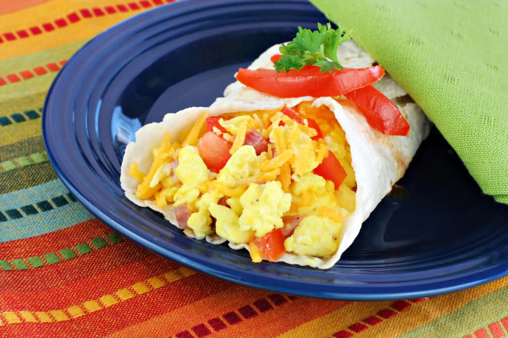 Delicious breakfast egg, tomato, cheese and pepper burrito.