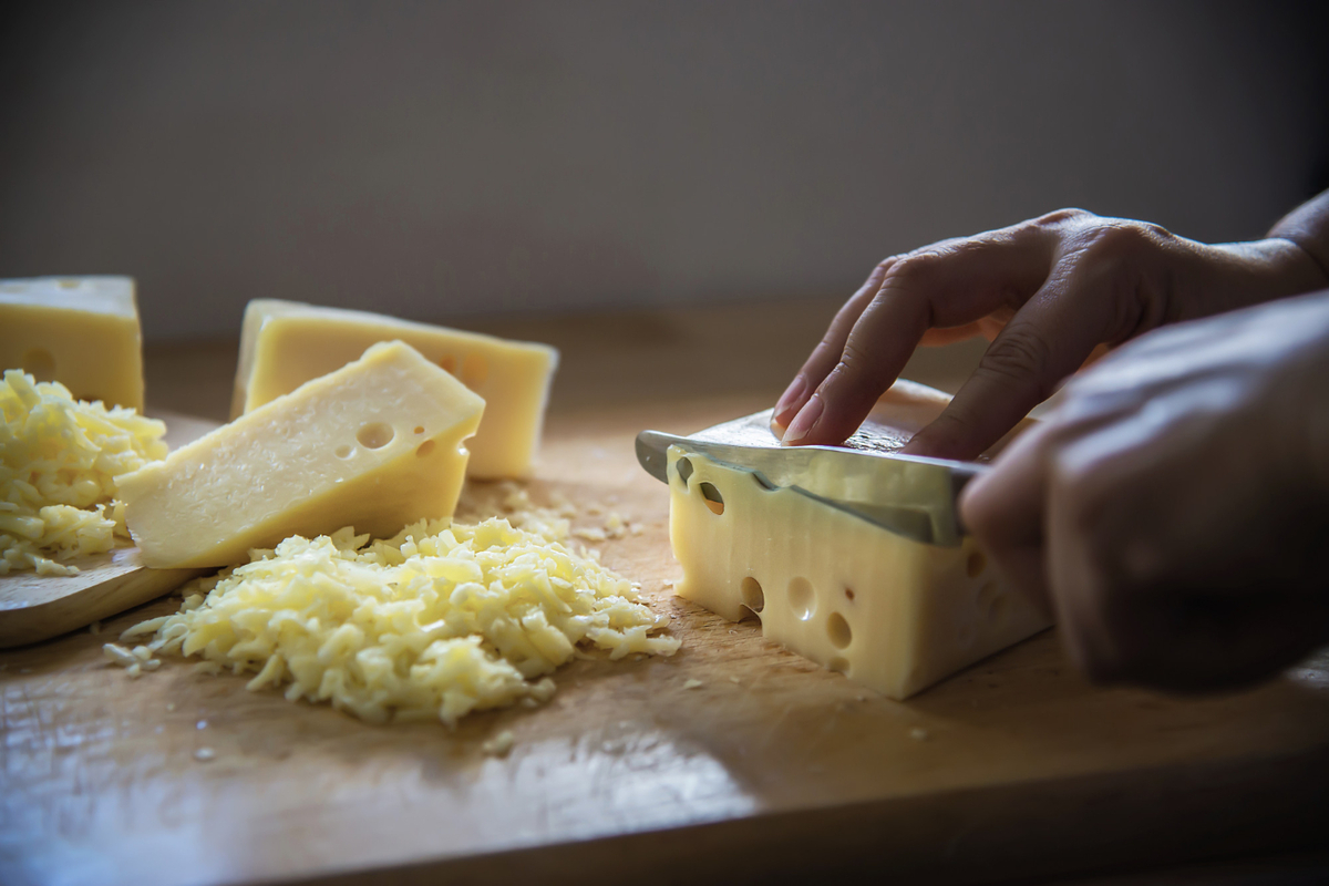 Woman cut slice cheese for cook using knife in the kitchen