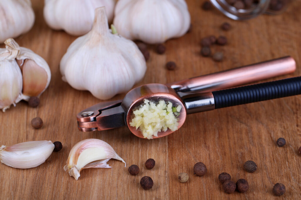 Garlic press on wooden background