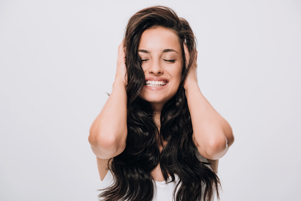 Happy brunette beautiful woman touching long curly healthy hair