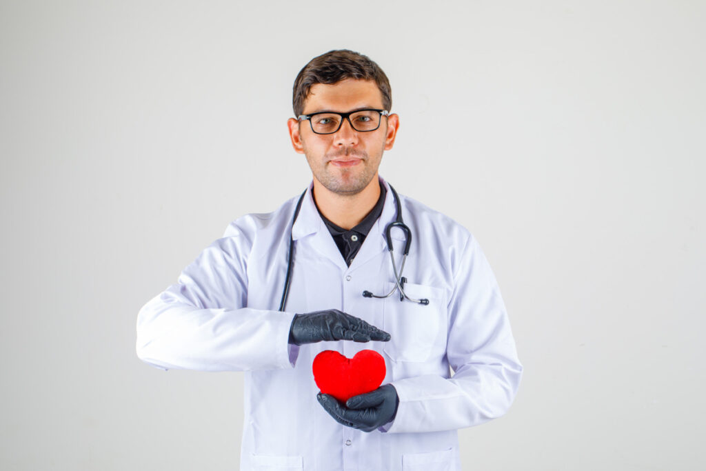 Doctor holding heart in white coat with stethoscope and looking positive